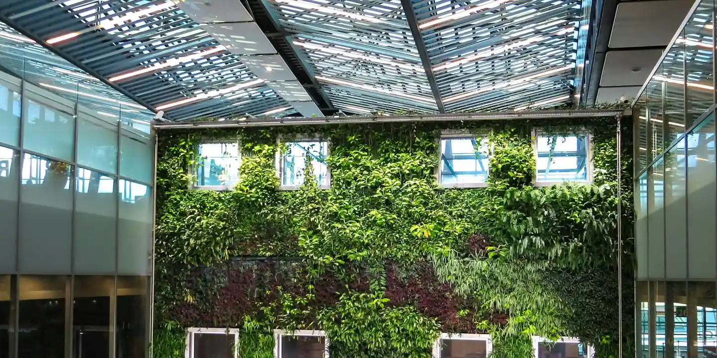 Indoor glass-roofed atrium with a lush ivy-covered brick wall and skylights.