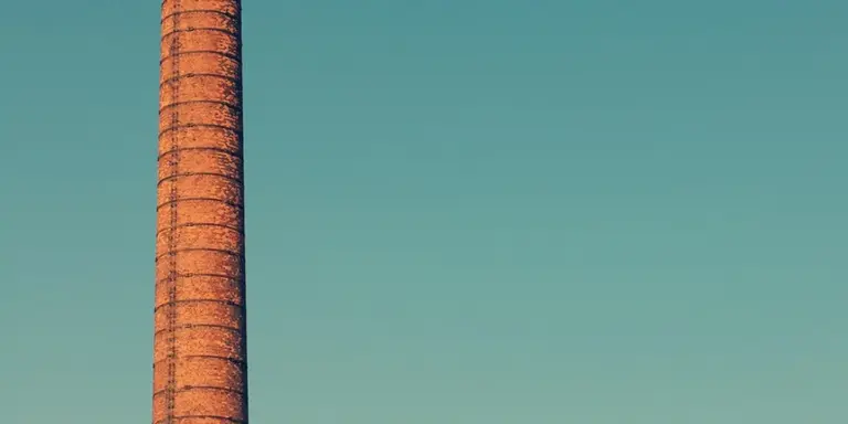 Close-up of a tall brick chimney stack against a clear blue sky