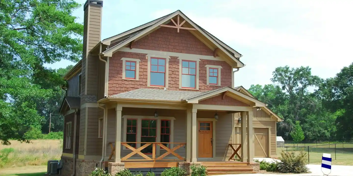 Two-story Craftsman-style house with a visible chimney on the roof, front porch, and green landscape.