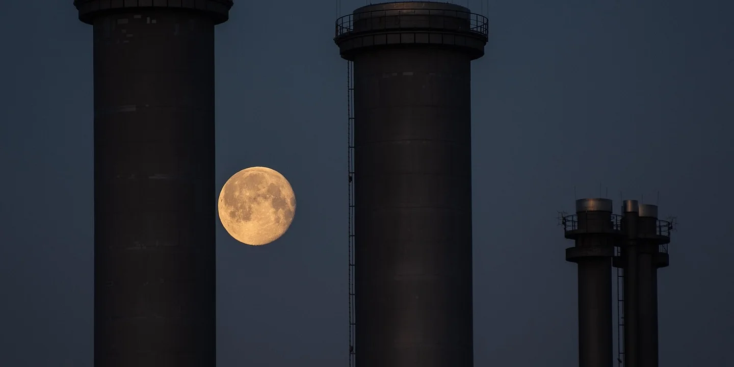 Moonlit night scene with tall chimney stacks against a dark blue sky.