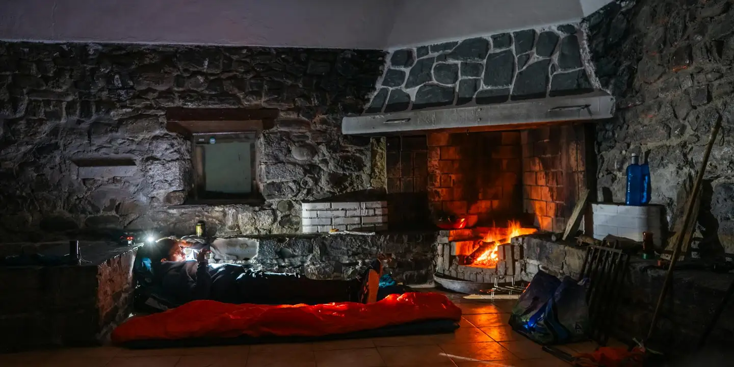 Interior view of a stone fireplace with glowing embers and firefighters assessing damage at the scene.