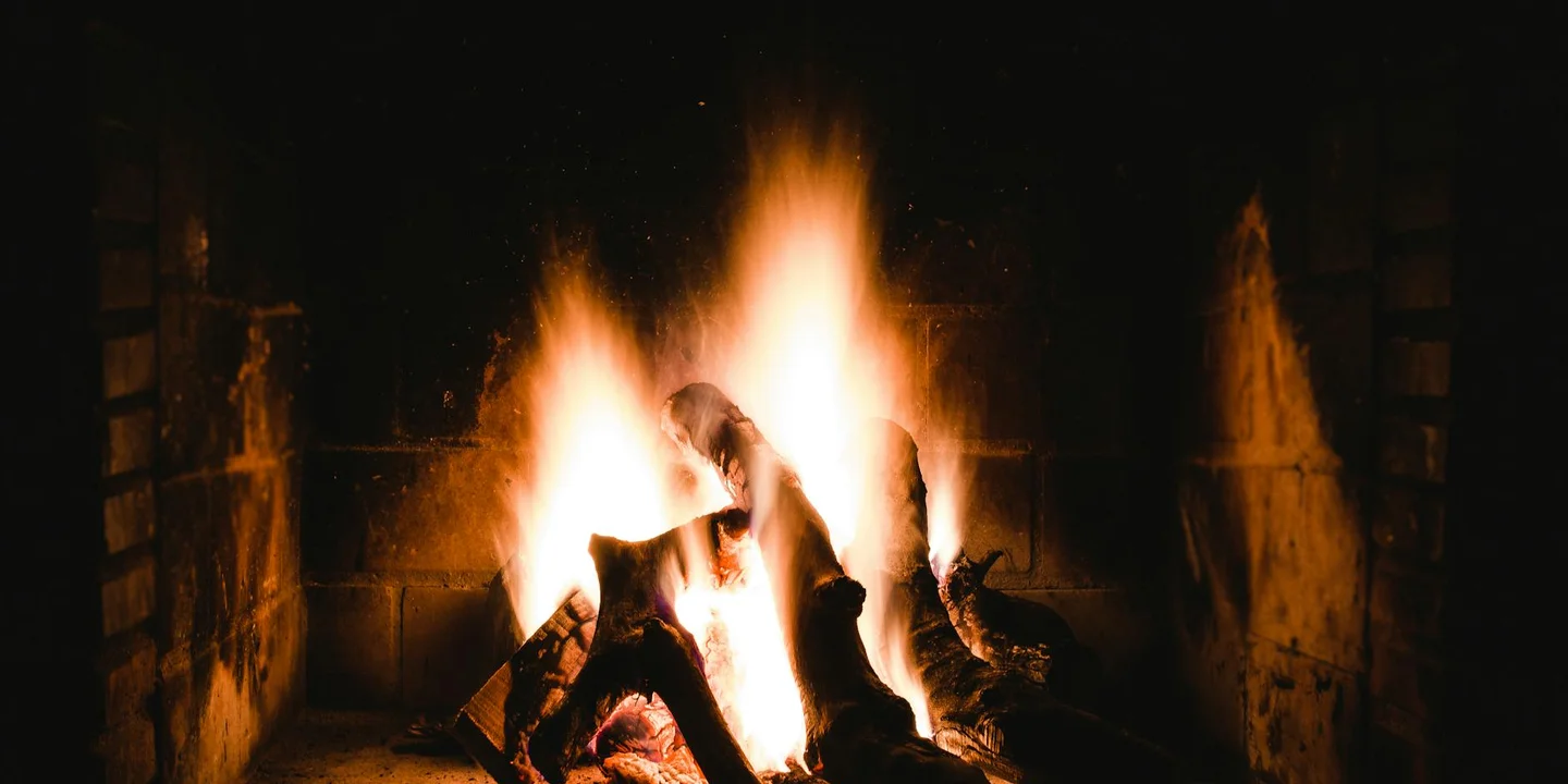 Fire burning inside a brick fireplace with bright orange flames.