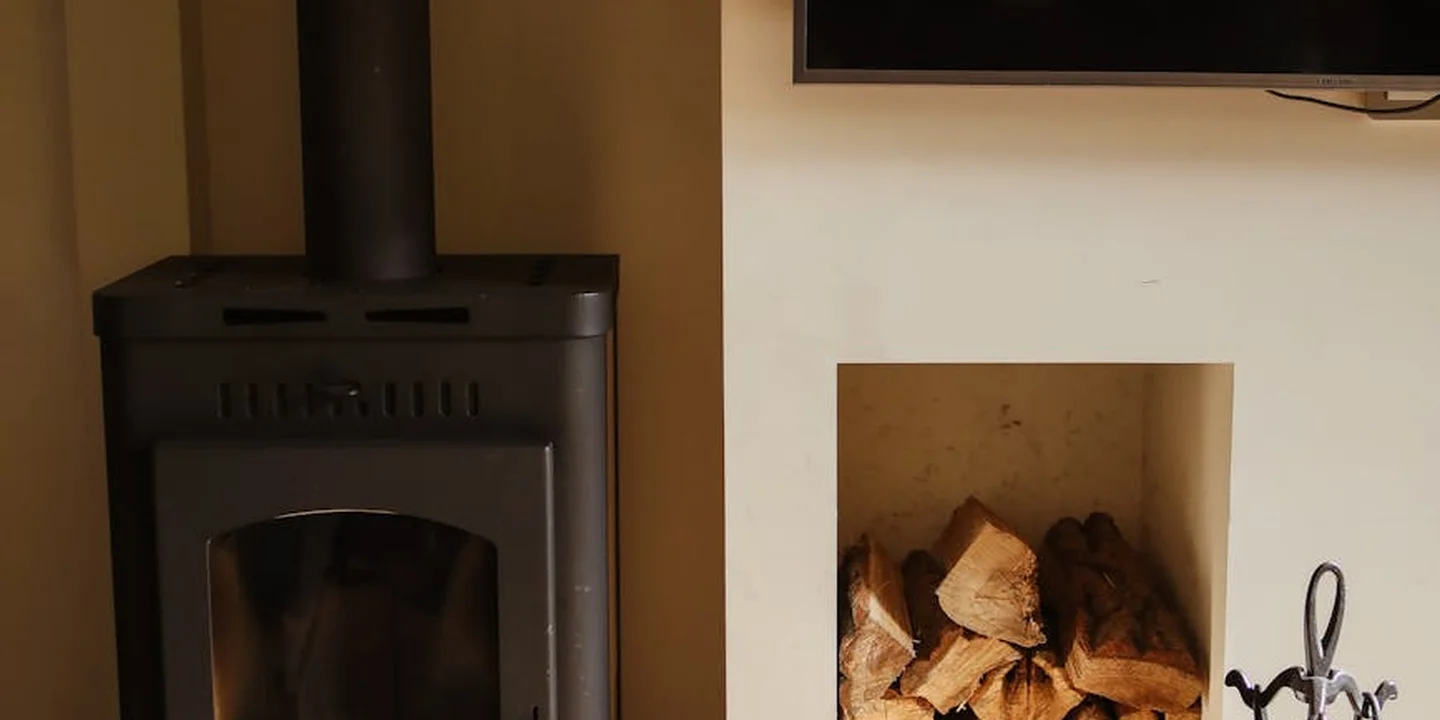 Wood-burning stove on the left with a stack of firewood in a recessed fireplace on the right