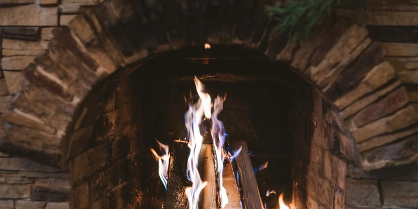 Fireplace with a glowing fire inside a brick surround, illustrating prep for chimney liner installation.
