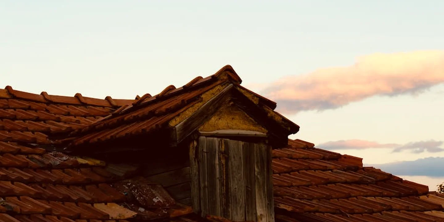 A clay tile roof with a small wooden gable-end vent protruding near the peak.