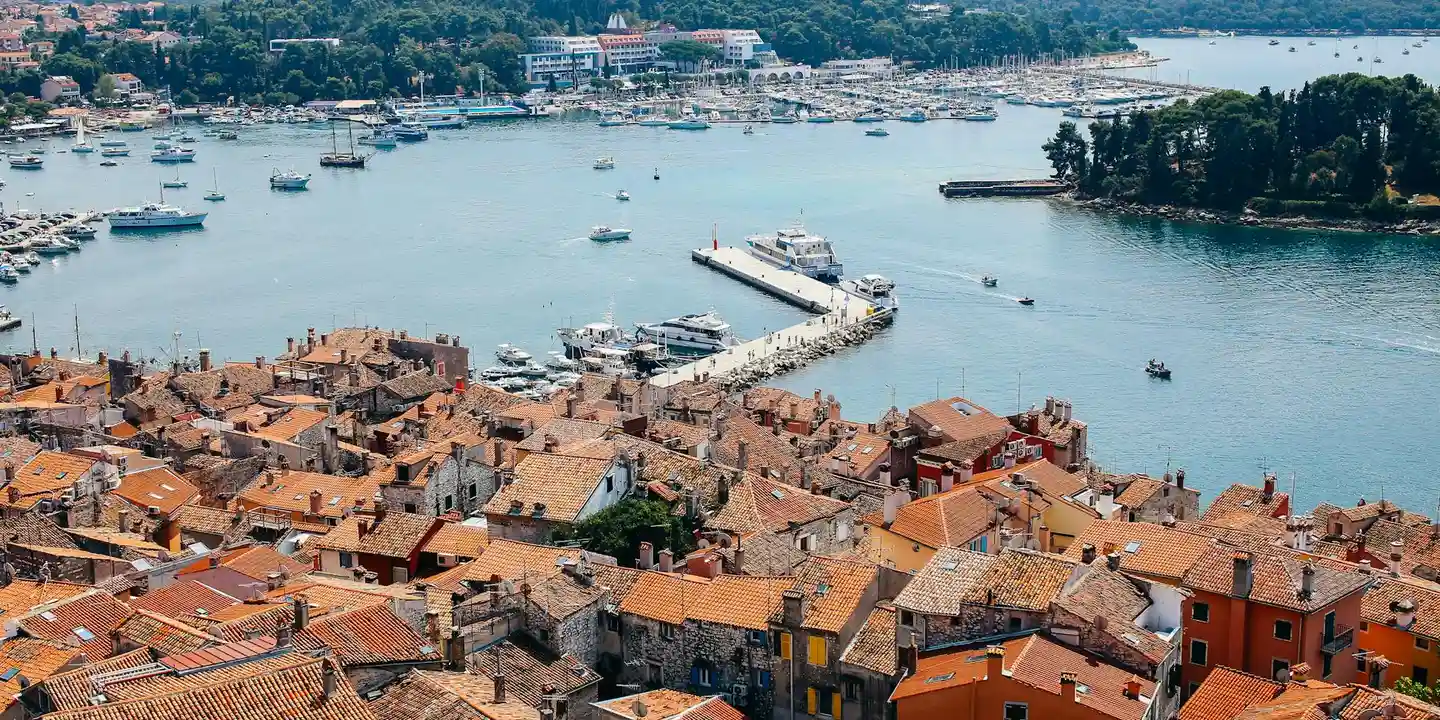 A coastal town with densely packed red clay tile roofs along a harbor, illustrating varied roof pitches and tile overlaps.