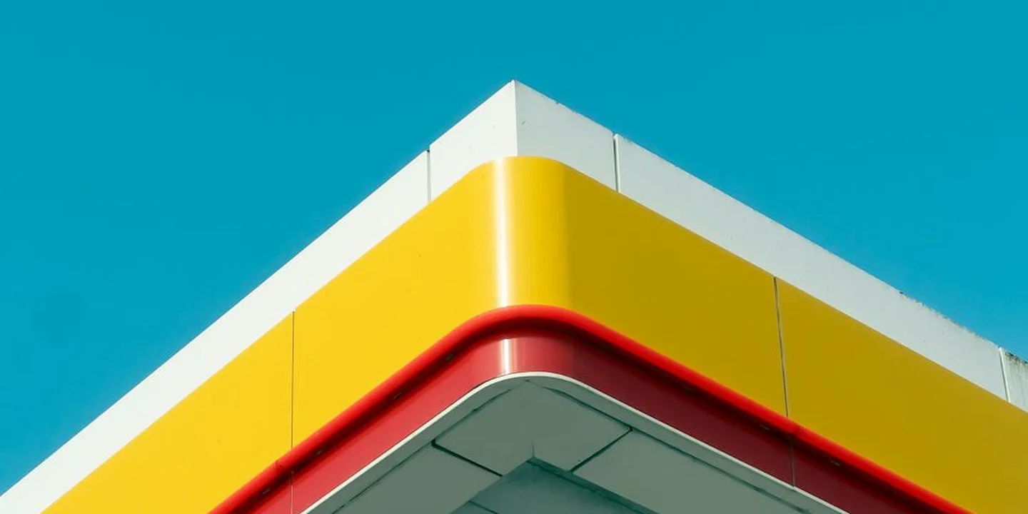 Close-up of a commercial roof edge with yellow metal panels and a red sealing gasket against a clear blue sky