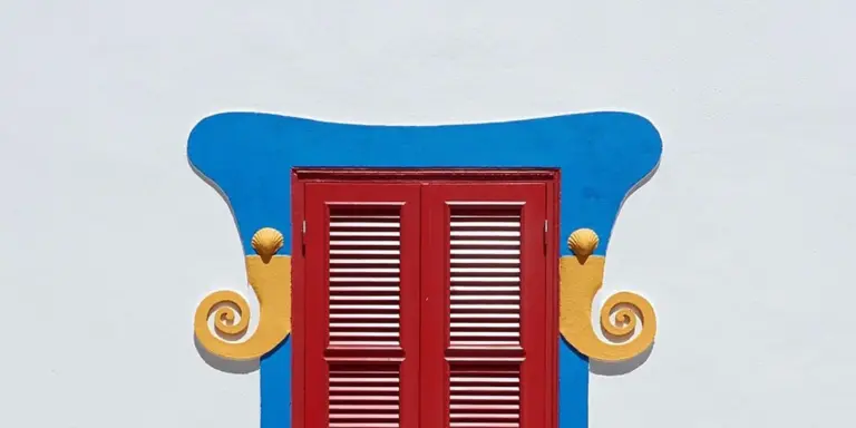 Colorful decorative doorway with a blue curved top, red panel doors, and yellow scroll accents on the sides.