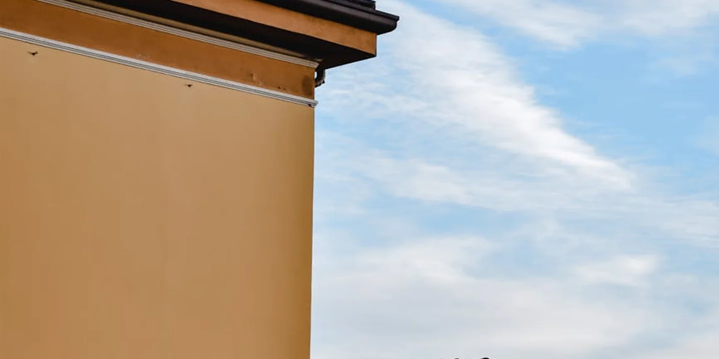 Exterior view of a house with an orange-brown wall and roofline against a blue sky