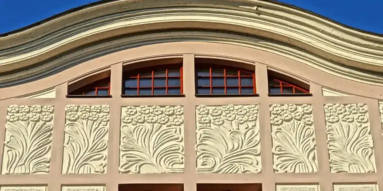 Decorative gable over a doorway with curved arch and embossed floral panels on the facade.