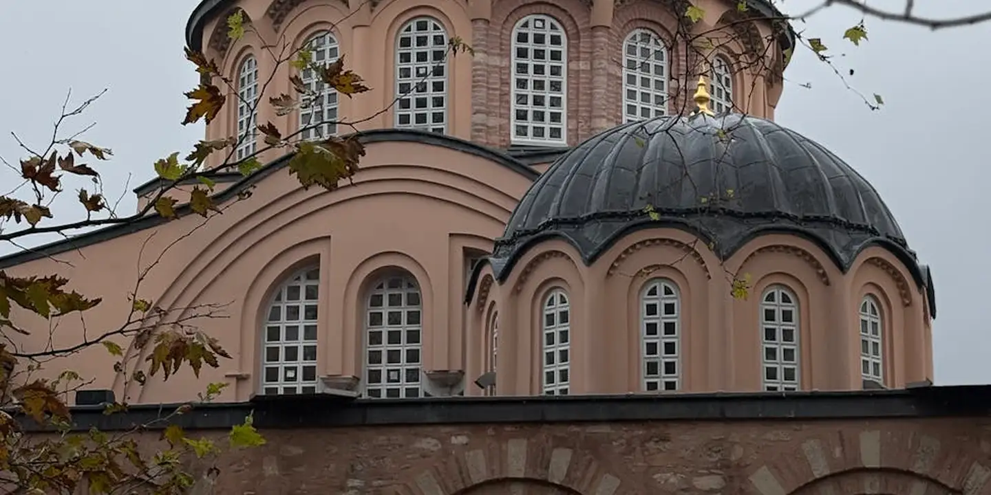 Exterior view of a historic building featuring a large central dome and arched windows, illustrating complex roof geometry and symbol-rich surfaces.
