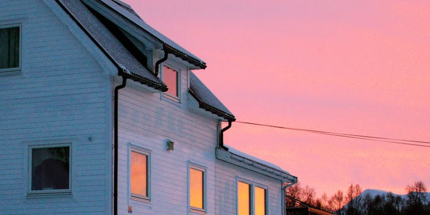 White house with a sloped roof under a pink sunset sky