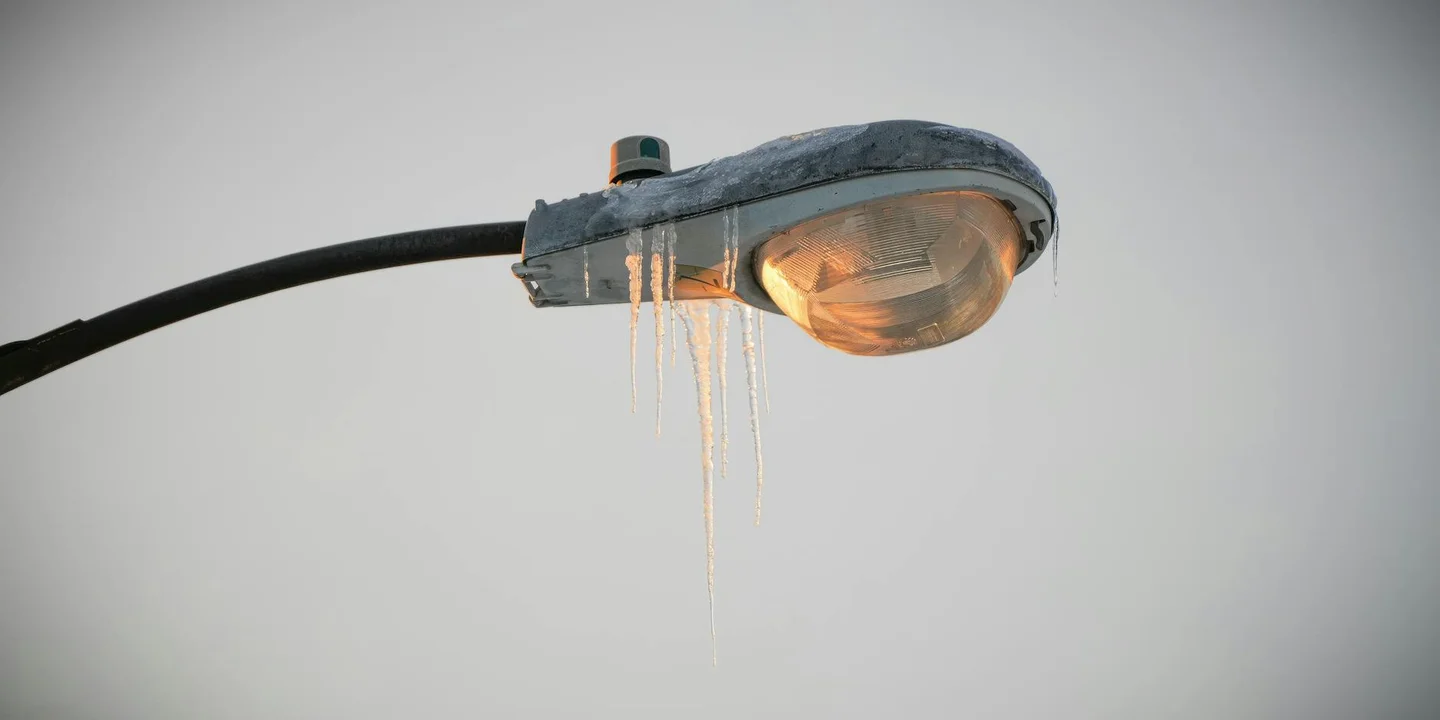 Icicles hanging from a streetlight, illustrating ice buildup from heat escaping from a roof