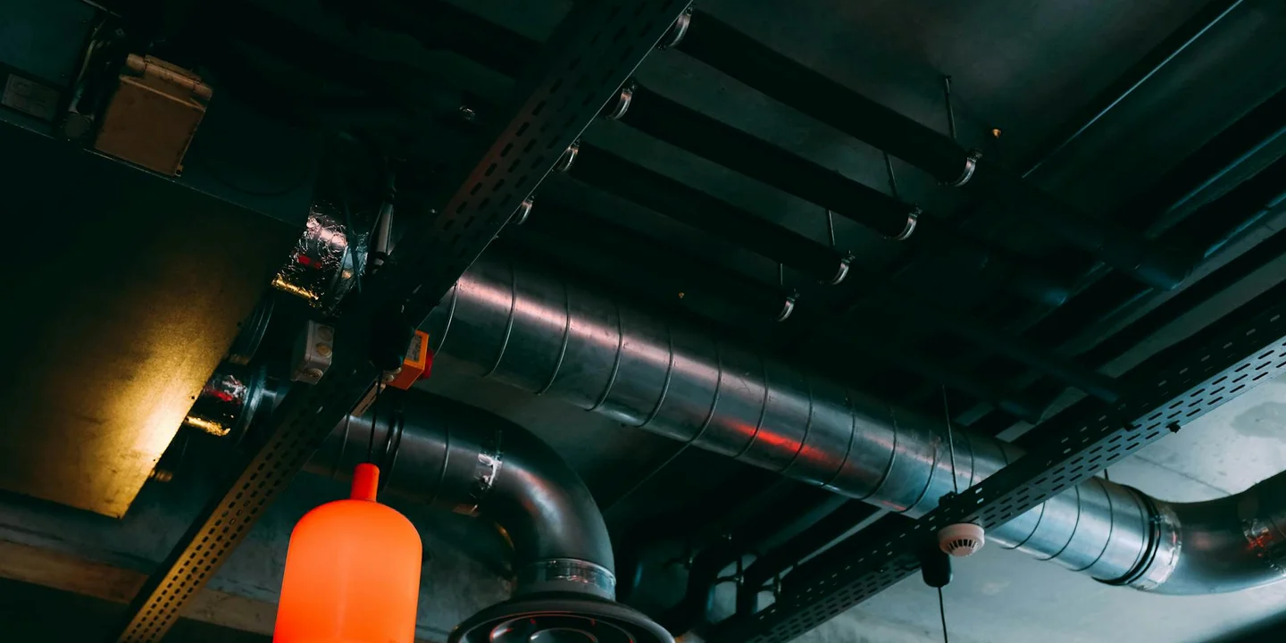 Interior ceiling space with exposed metal ducts and pipes, illustrating an indoor roof leak repair scenario.