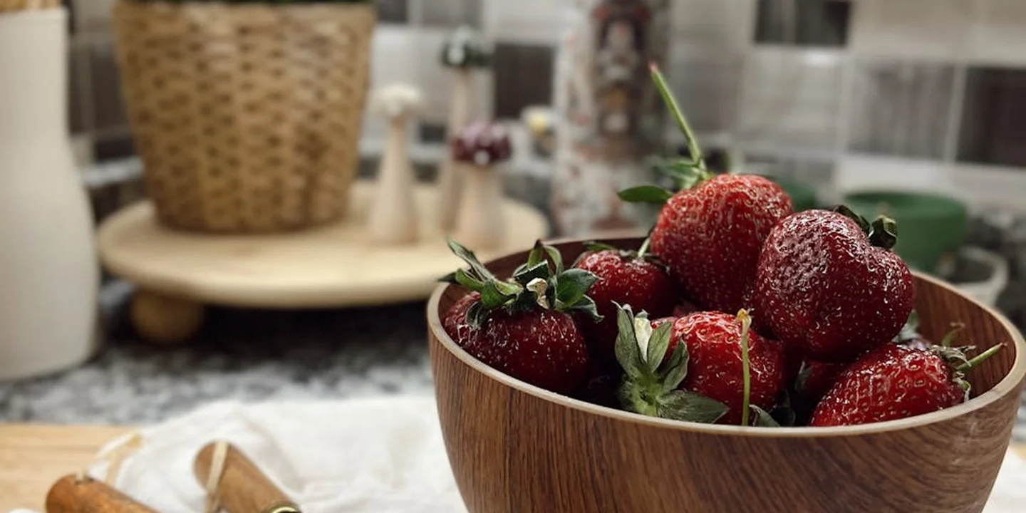 Fresh strawberries in a wooden bowl on a kitchen counter