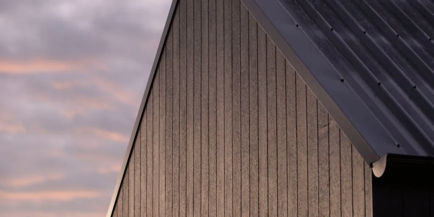 Close-up of a dark metal roof with vertical seams, captured at sunset.