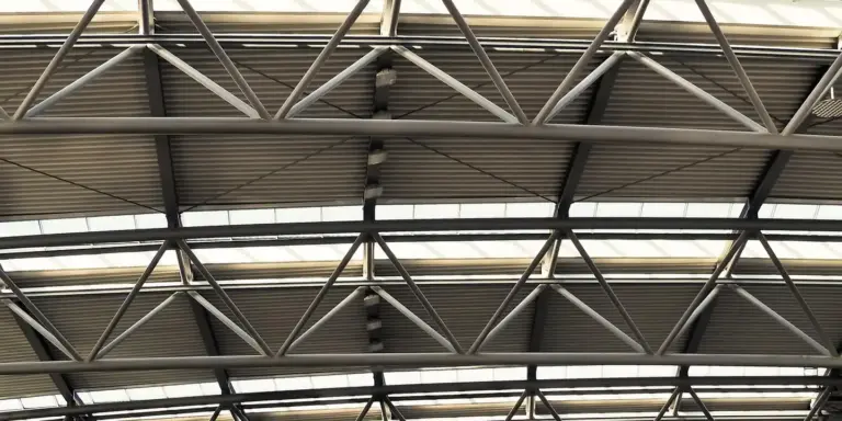Interior view of a metal roof structure with steel trusses and corrugated panels