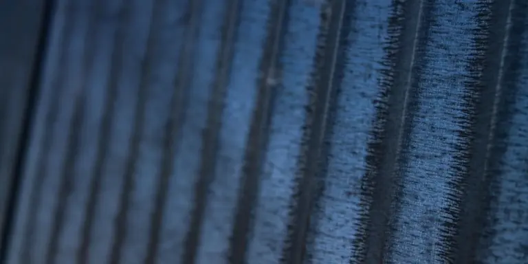Close-up of textured metal roofing panels with visible seams and surface detail.