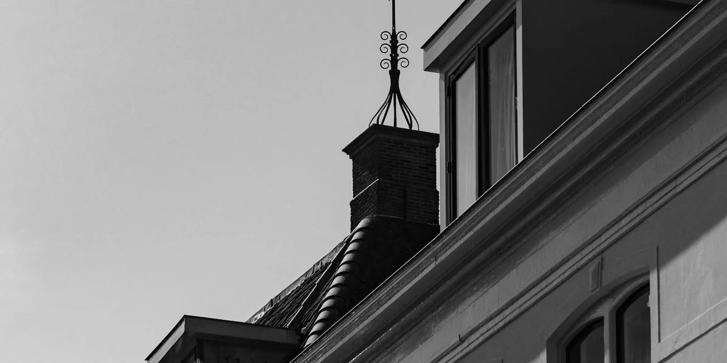 Close-up of the edge of a pitched metal roof with a chimney.