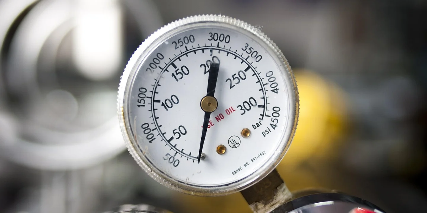 Close-up of a circular pressure gauge on a pressure washing tool, with a white dial and black needle across a scale.