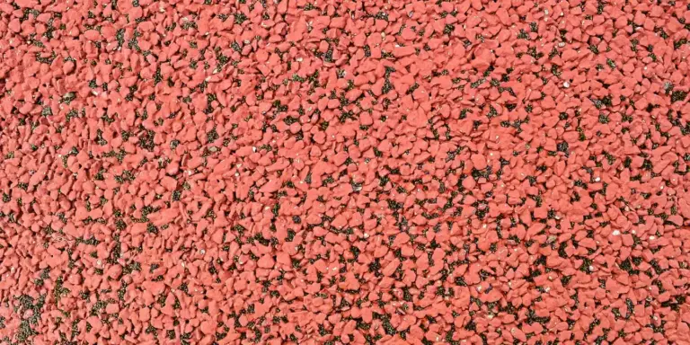 Close-up of red roofing ballast (crushed stone) on a flat residential roof.