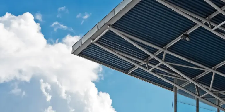 Close-up of metal roof panels and supporting structure against a bright blue sky