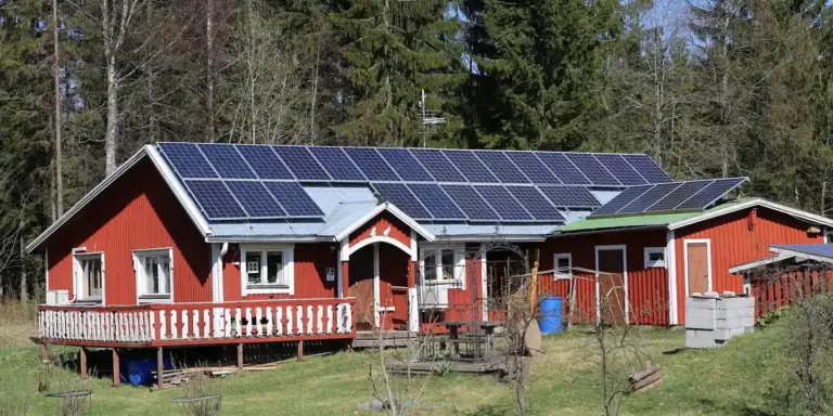 Red house with solar panels installed on its sloped roof.