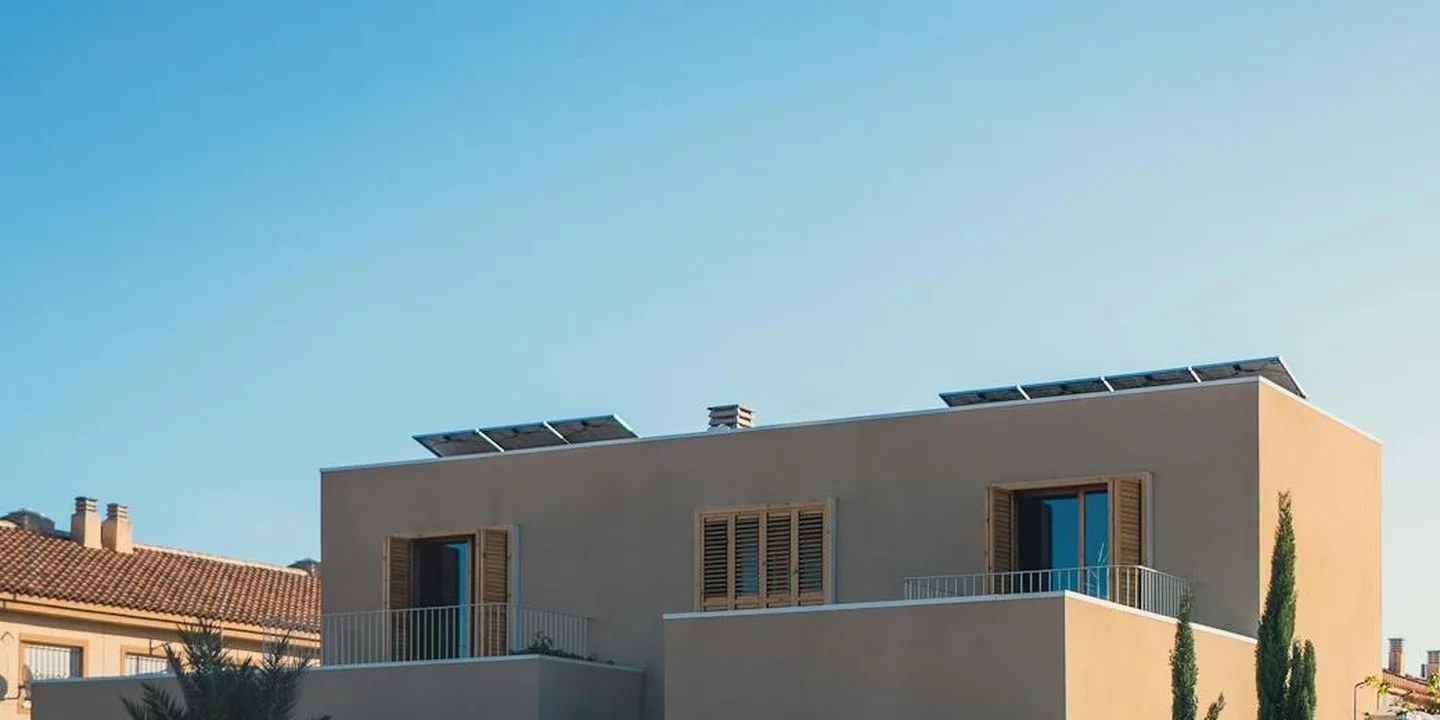 Modern beige residential roof with installed solar panels under a clear blue sky.