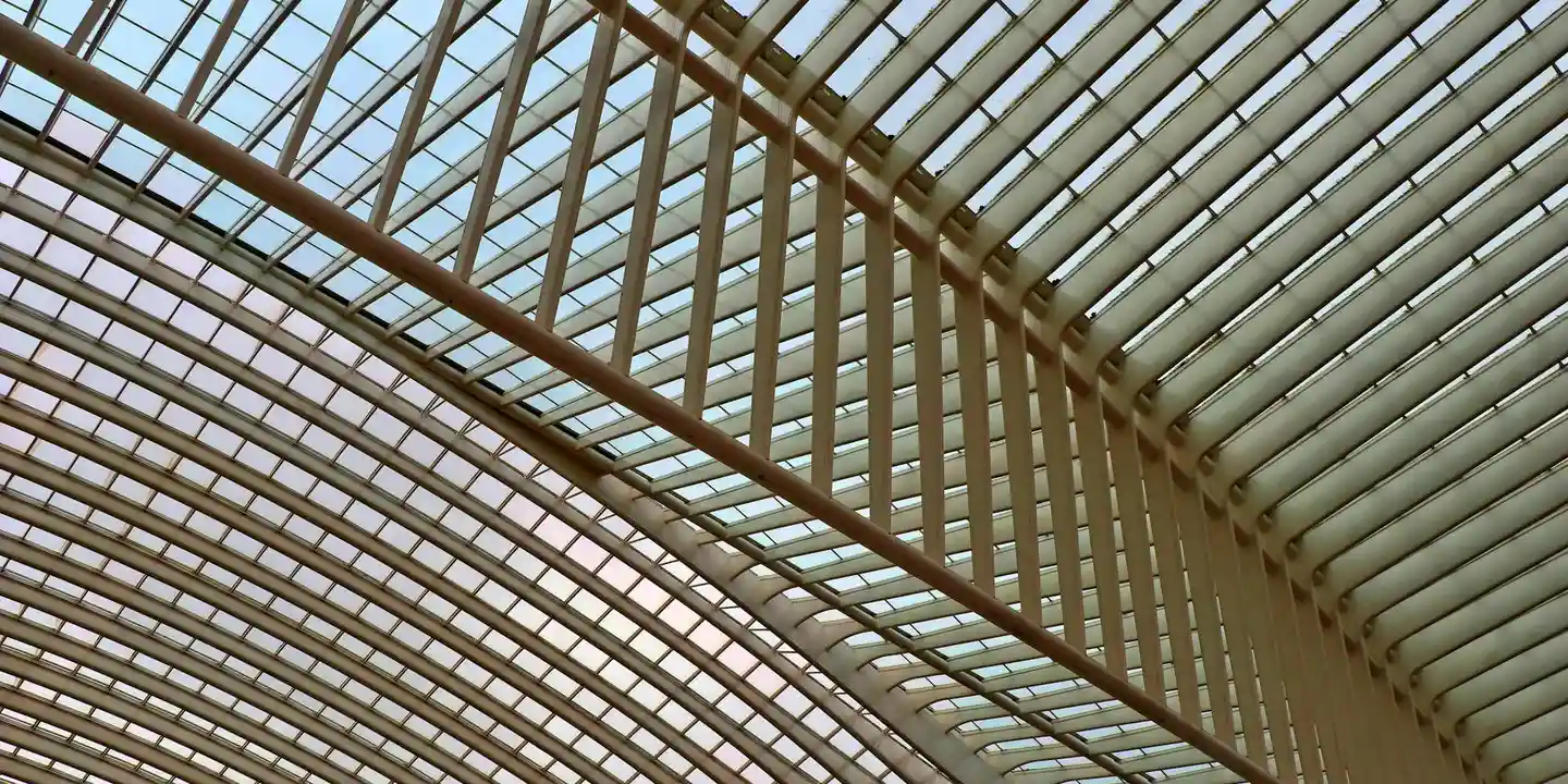 Interior view of a glass skylight roof with metal framing and supporting beams