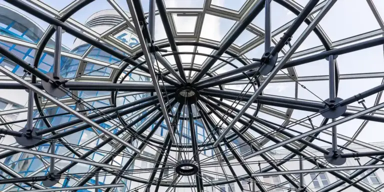 Circular glass skylight with an intricate metal framework forming radial spokes around a central hub
