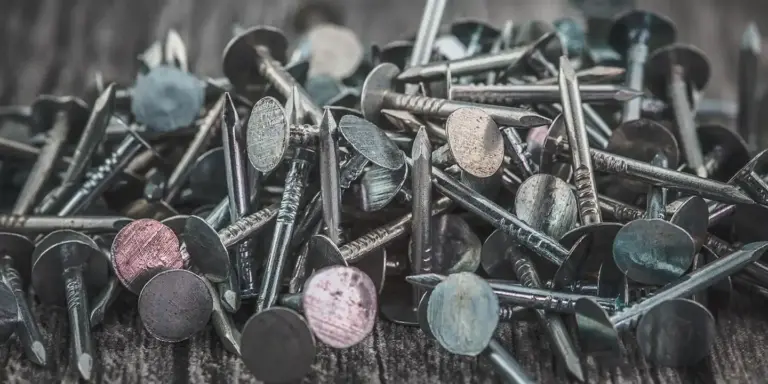 Close-up of metal roofing nails scattered on a wooden surface