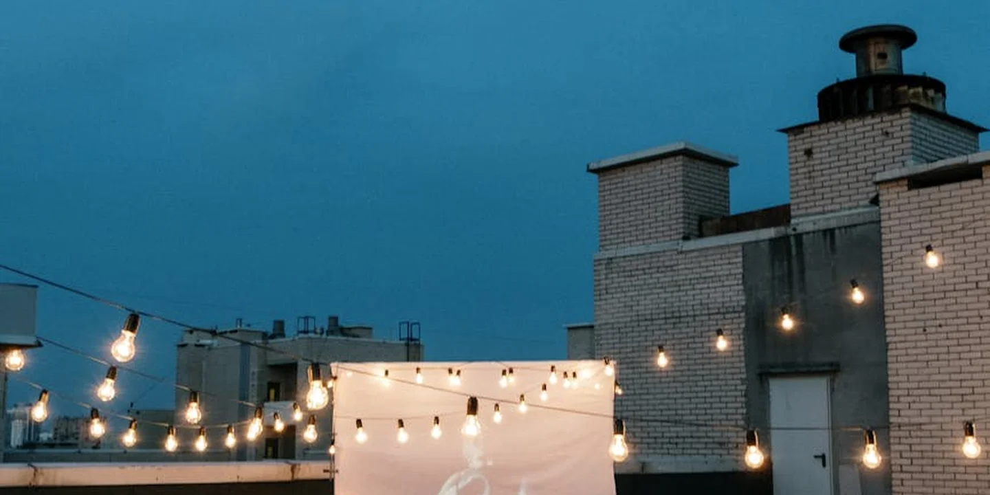 Rooftop with string lights at dusk, brick chimneys and a calm blue sky
