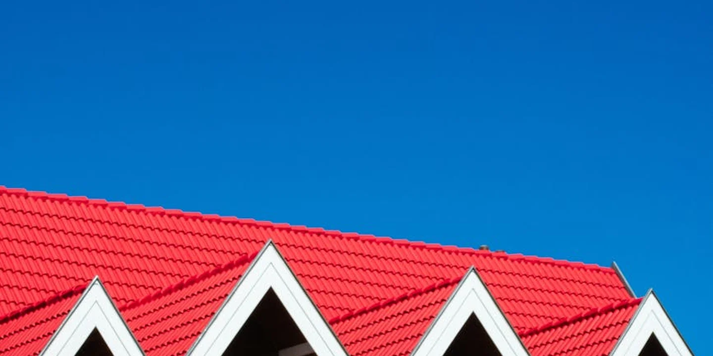 Red multi-gable roof with white trim set against a clear blue sky