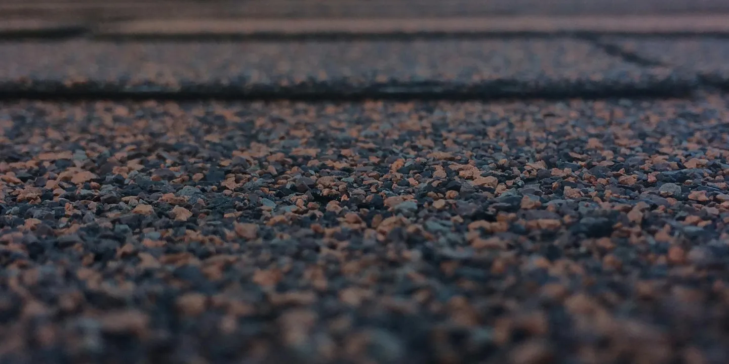 Close-up of asphalt roof shingles with loose granules, illustrating the surface to be cleaned.