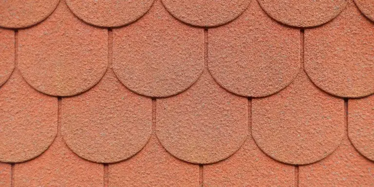 Close-up of warm terracotta roof shingles with rounded edges, showing texture and color variation.