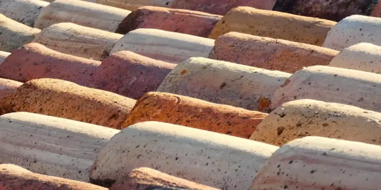 Close-up of interlocking, curved roof tiles in various earthy colors arranged in overlapping rows
