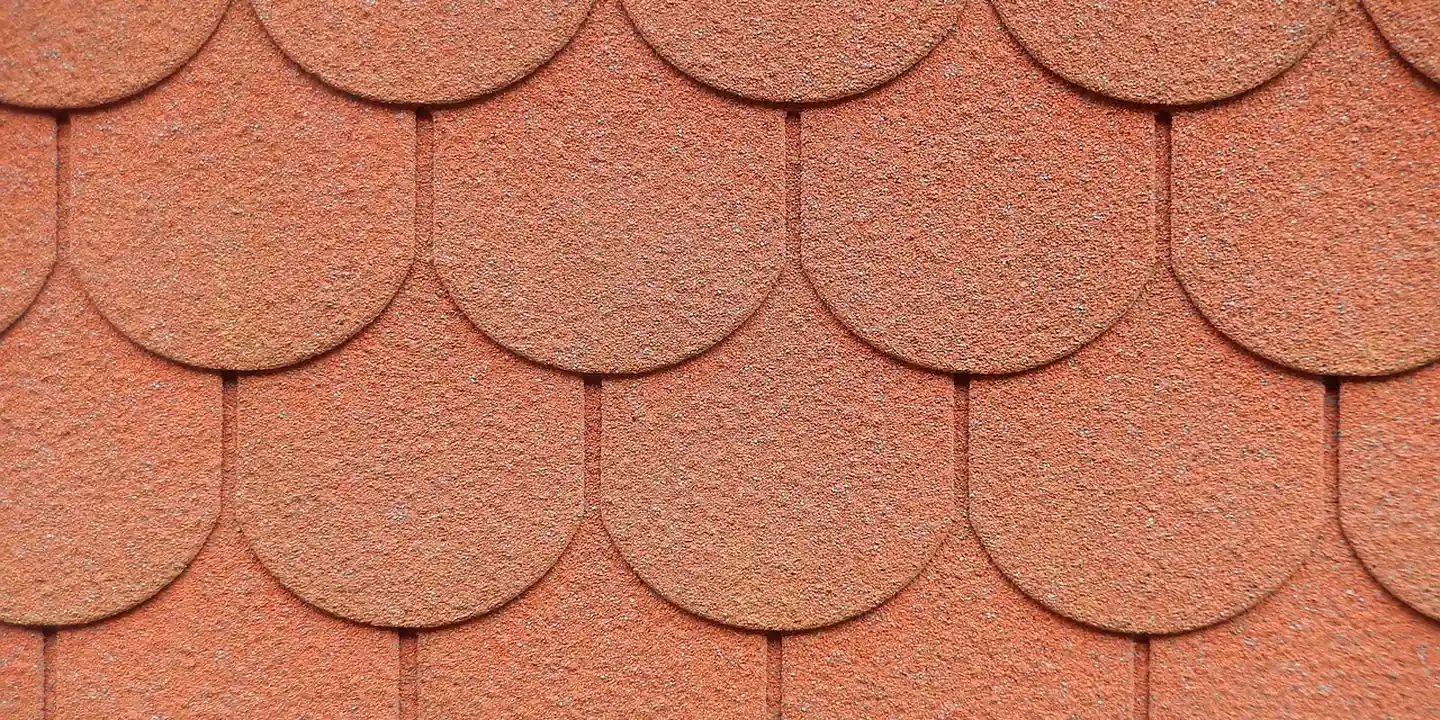 Close-up view of overlapping orange-brown roof shingles.
