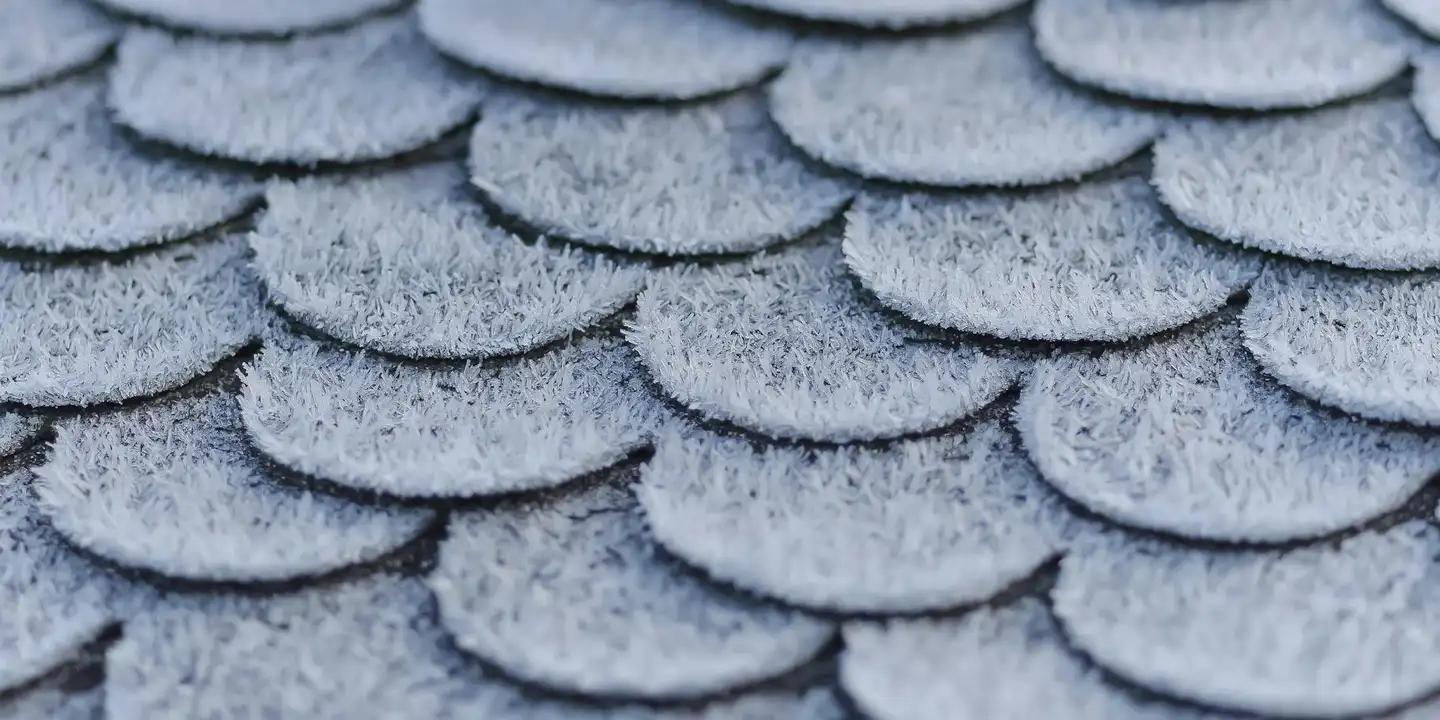 Close-up of overlapping gray asphalt roof shingles, showing texture and subtle color variation.