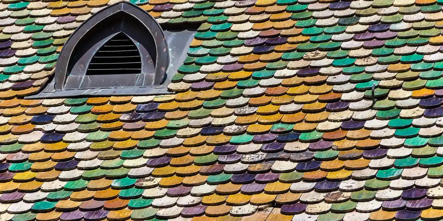 Close-up of multicolored asphalt shingles and a small roof vent.