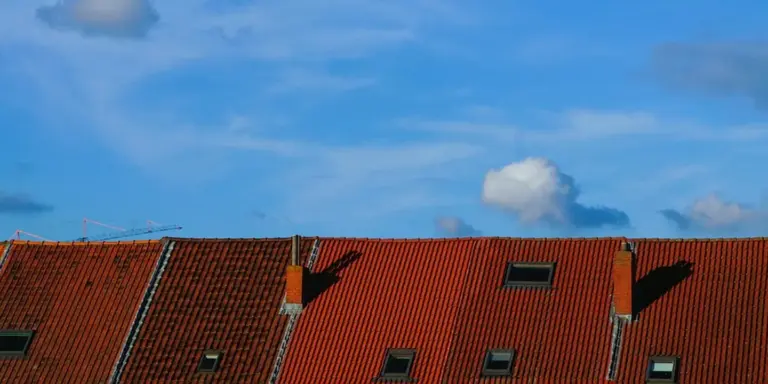 Red tiled roof under a bright blue sky with a few clouds.