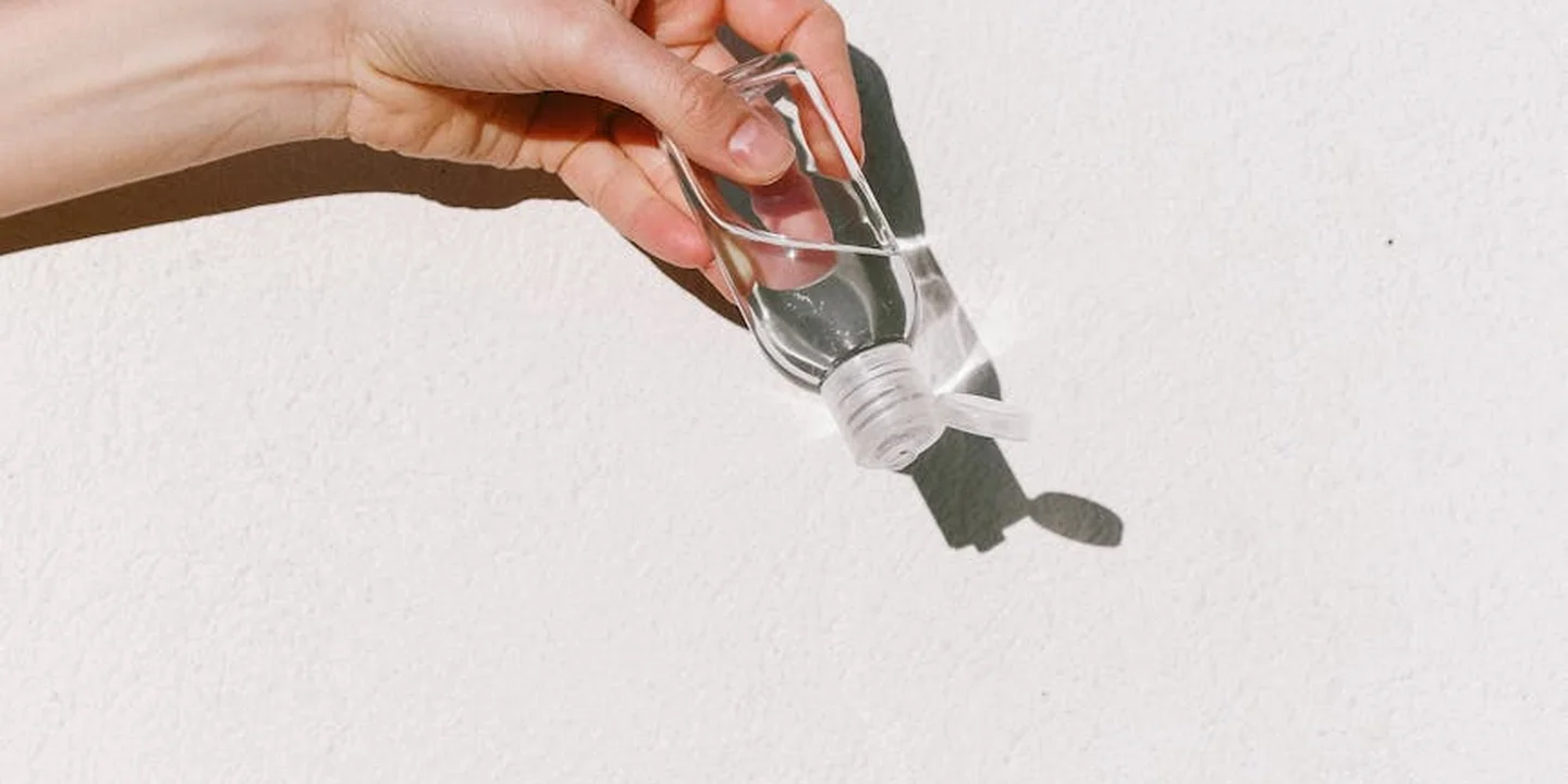Close-up of a hand squeezing a small bottle to dispense liquid