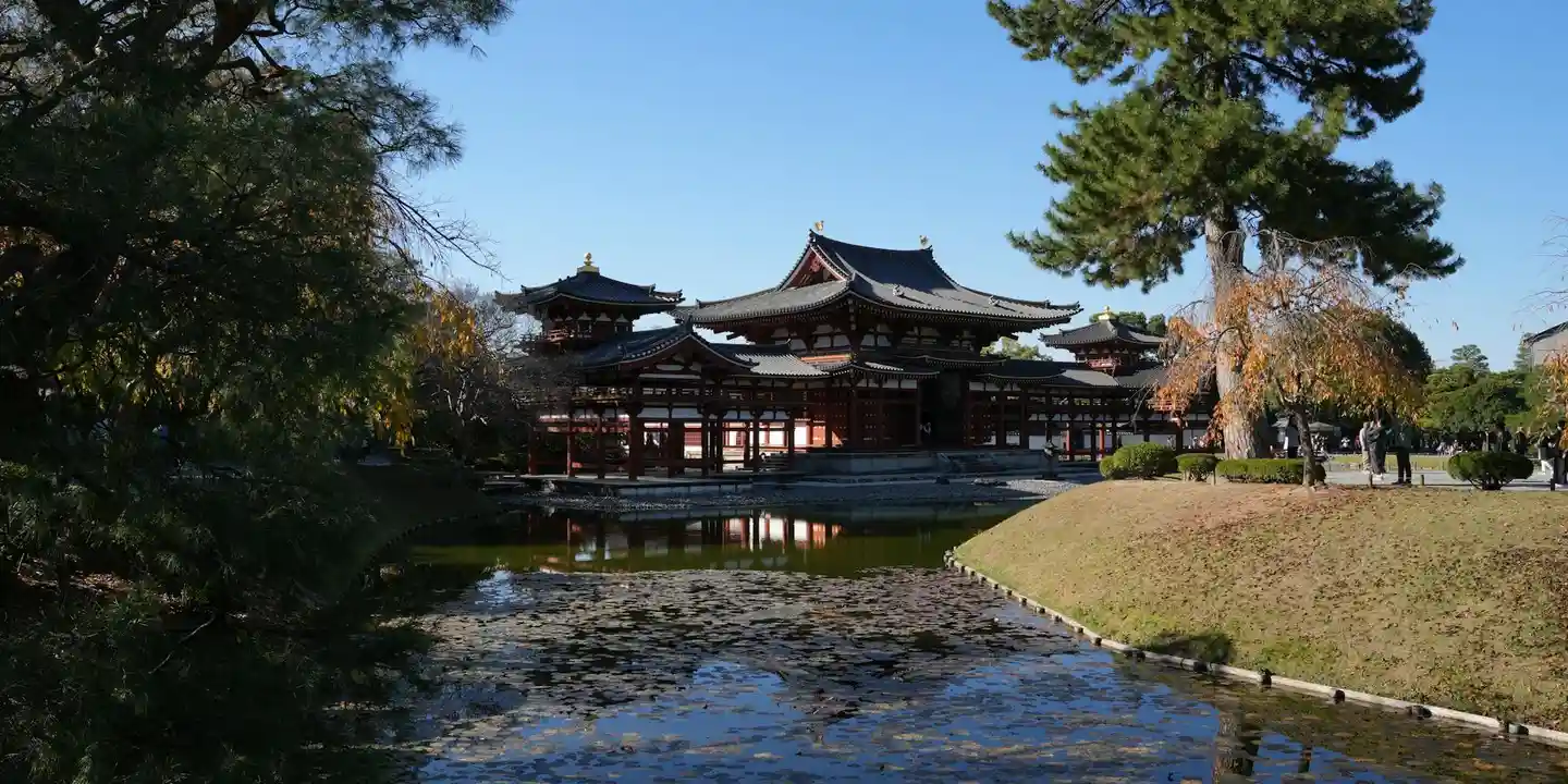 Slanted roof with dark ceramic tiles on a traditional Japanese temple, set beside a pond and landscaped grounds