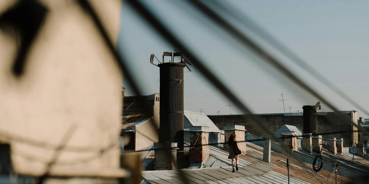 Rooftop view featuring multiple chimneys and cables, with a person walking on the roof