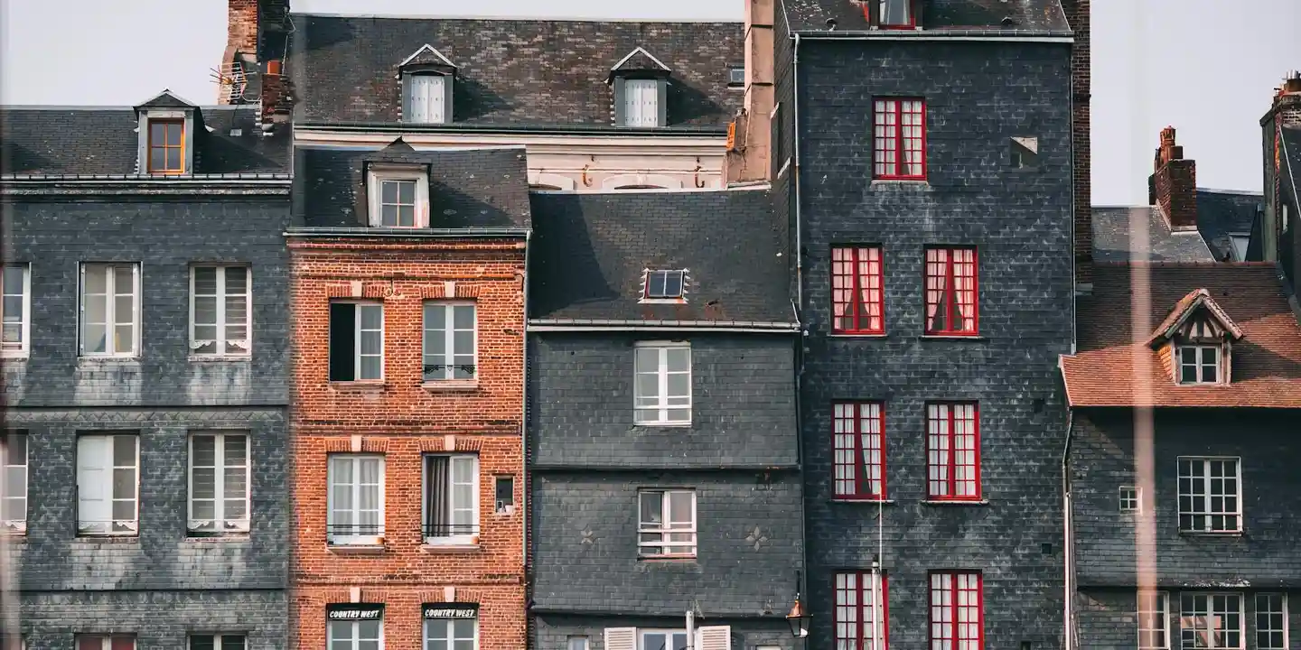 Row of old brick houses with dark slate roofs and multiple chimneys.