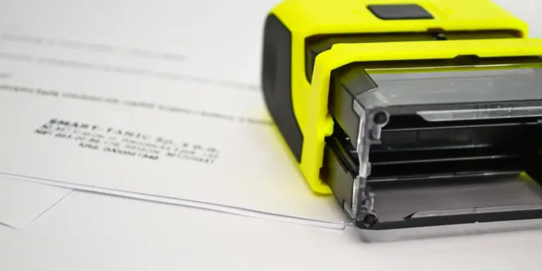 Close-up of a yellow roofing nailer on blueprint-style papers, illustrating installation tools for rubber roofing.