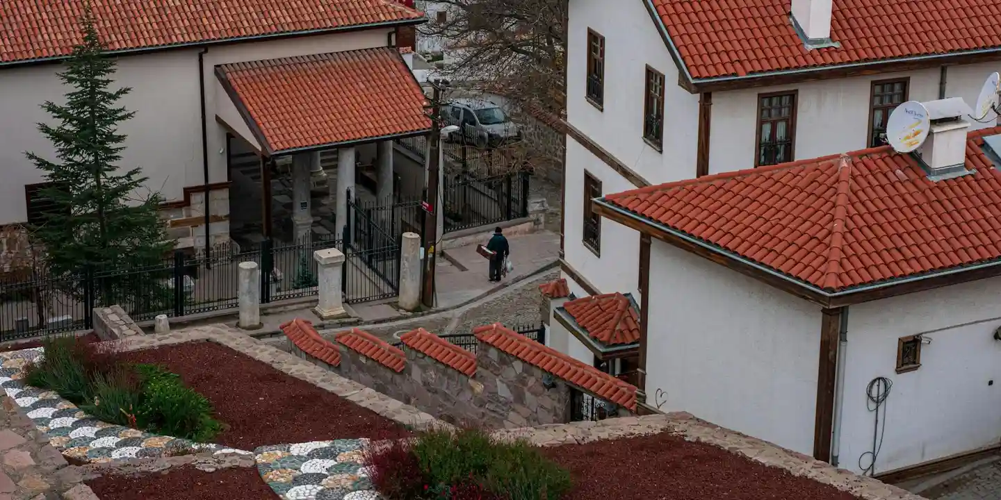 Residential complex with white walls and red Spanish tile roofs, featuring a courtyard and stone steps.