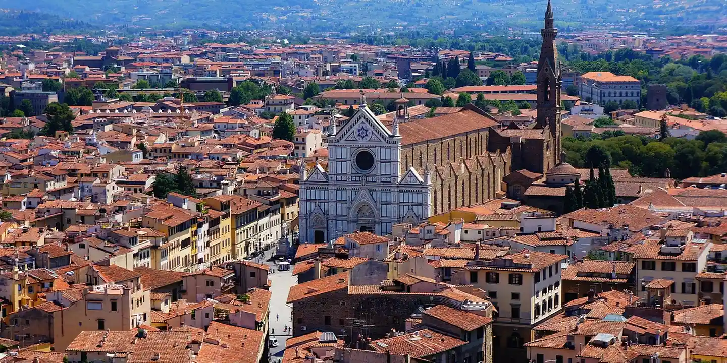 Aerial view of a historic Italian town with dense red-tiled roofs and a prominent stone church
