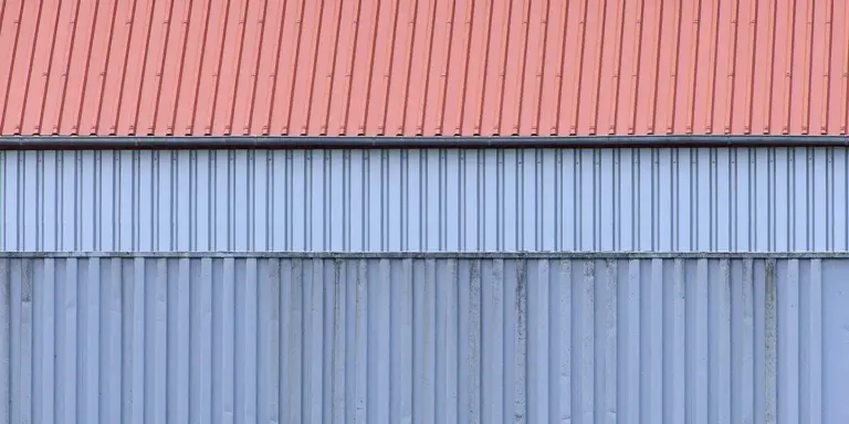 Blue corrugated metal panels with a red trim along the top, illustrating metal roofing material.