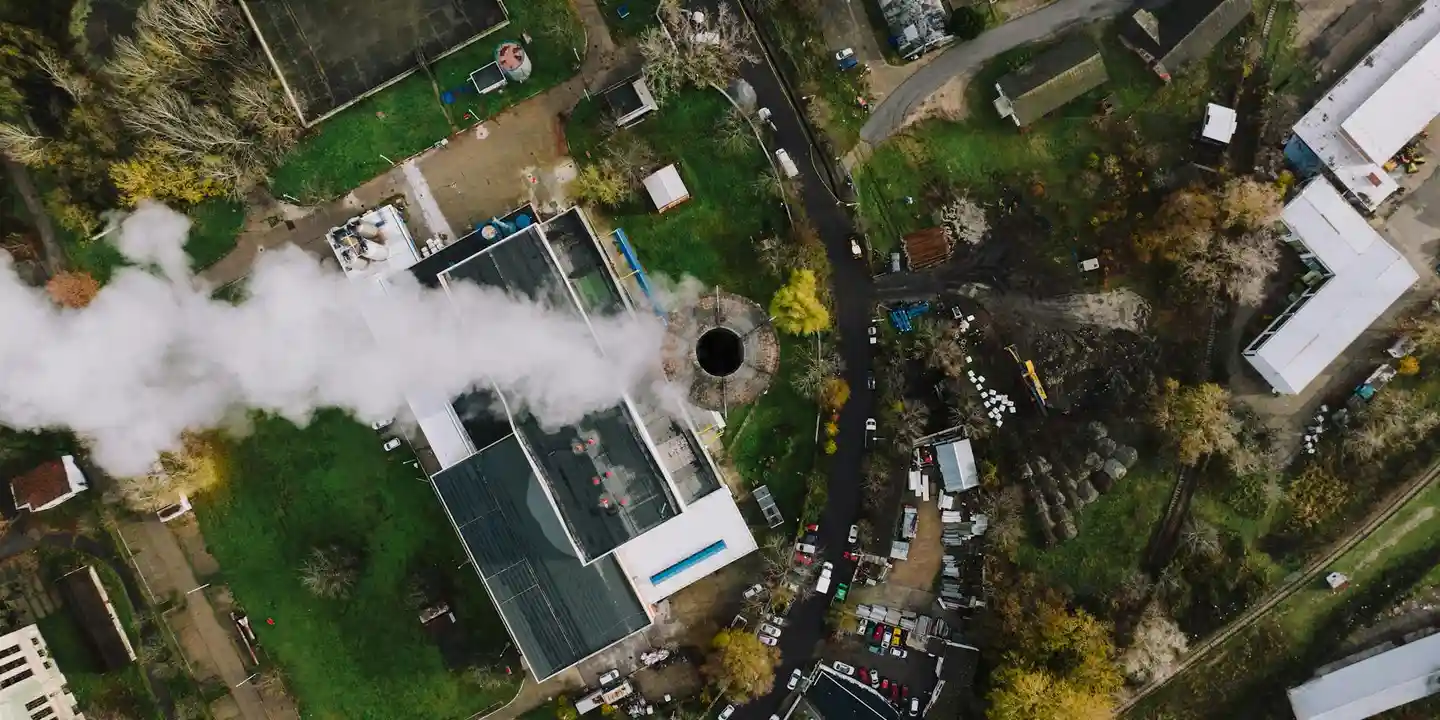 Aerial view of a residential roof with a prominent chimney vent and surrounding structures, illustrating potential leak points at flashing, crown, and mortar joints.