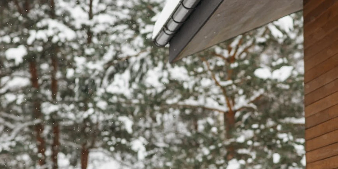 Snow-covered roof edge with a gutter, illustrating heat loss from the attic that can cause ice dams.